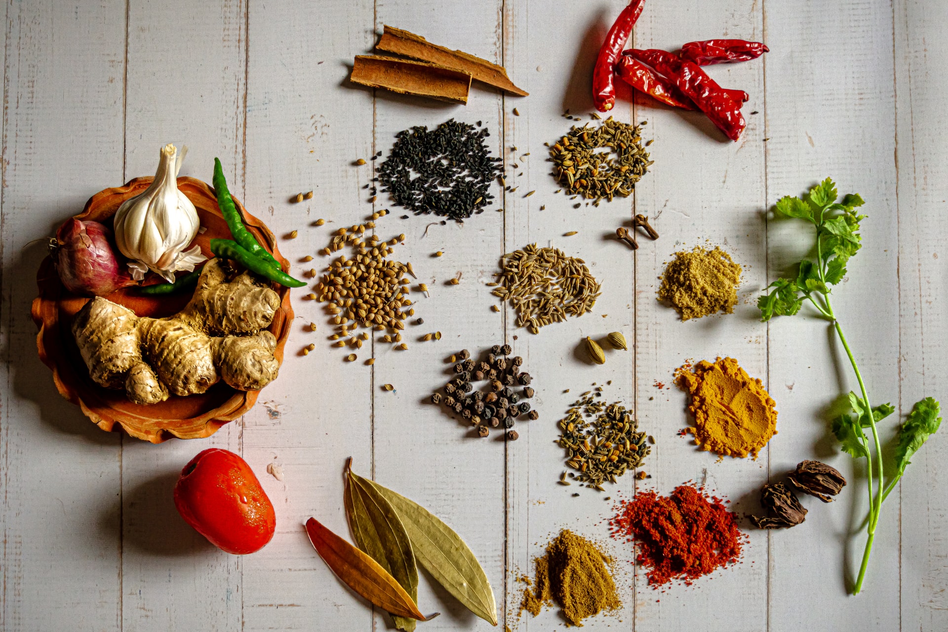 A variety of spices including ginger, garlic, peppercorn, cinnamon and more