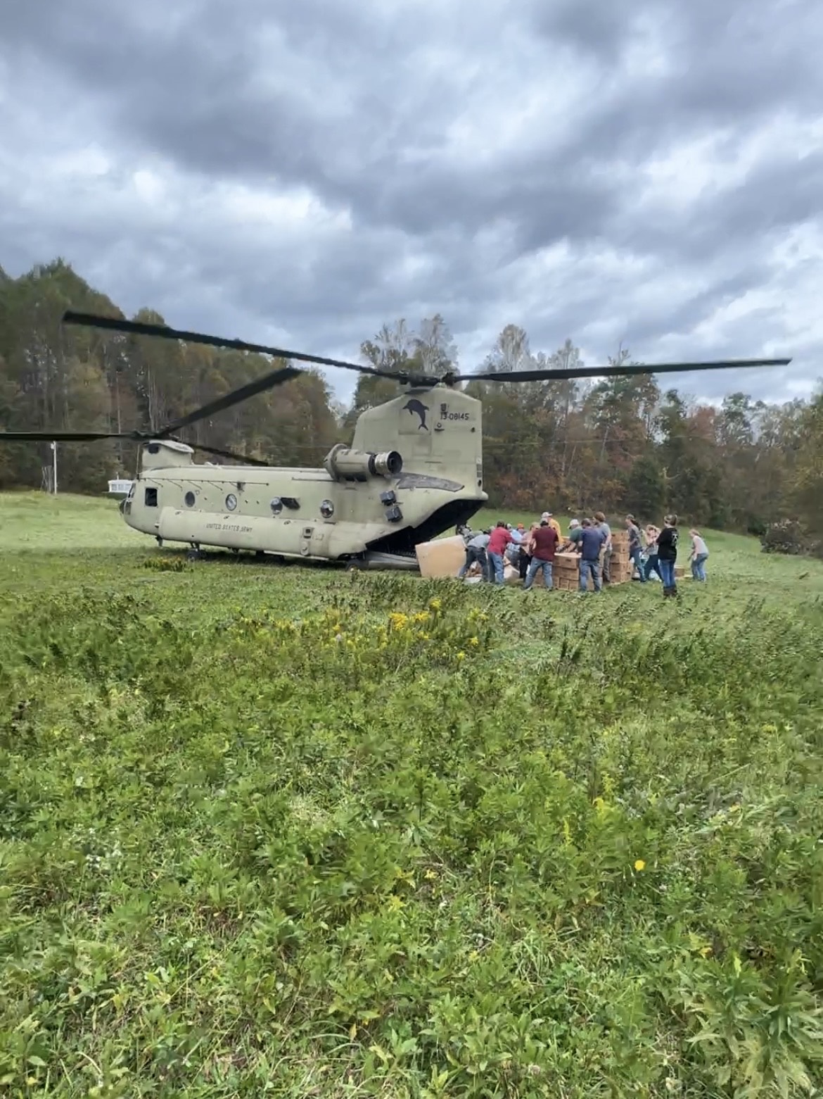 Helicopter in a field off loads supplies.